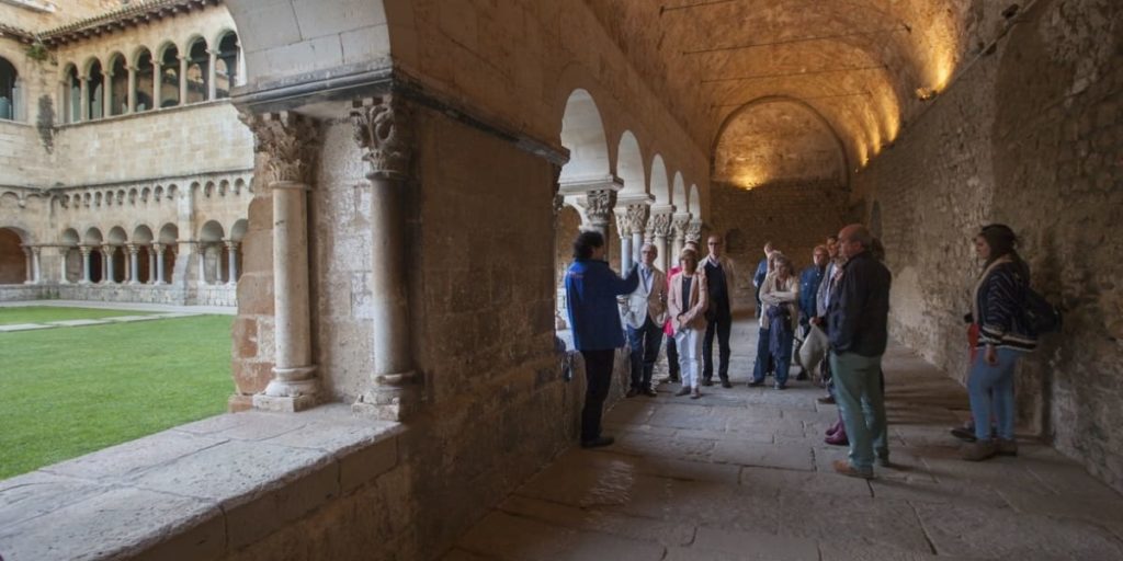 grup de persones escoltant les explicacions d'una guia al claustre del Monsetir de Sant Cugat del Vallès