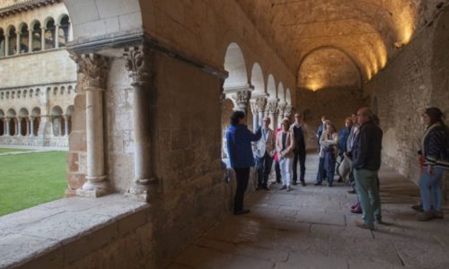 grup de persones escoltant les explicacions d'una guia al claustre del Monsetir de Sant Cugat del Vallès
