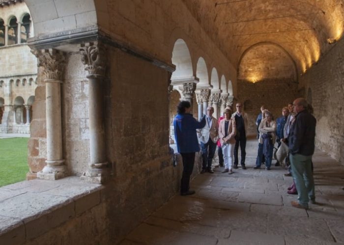 grup de persones escoltant les explicacions d'una guia al claustre del Monsetir de Sant Cugat del Vallès